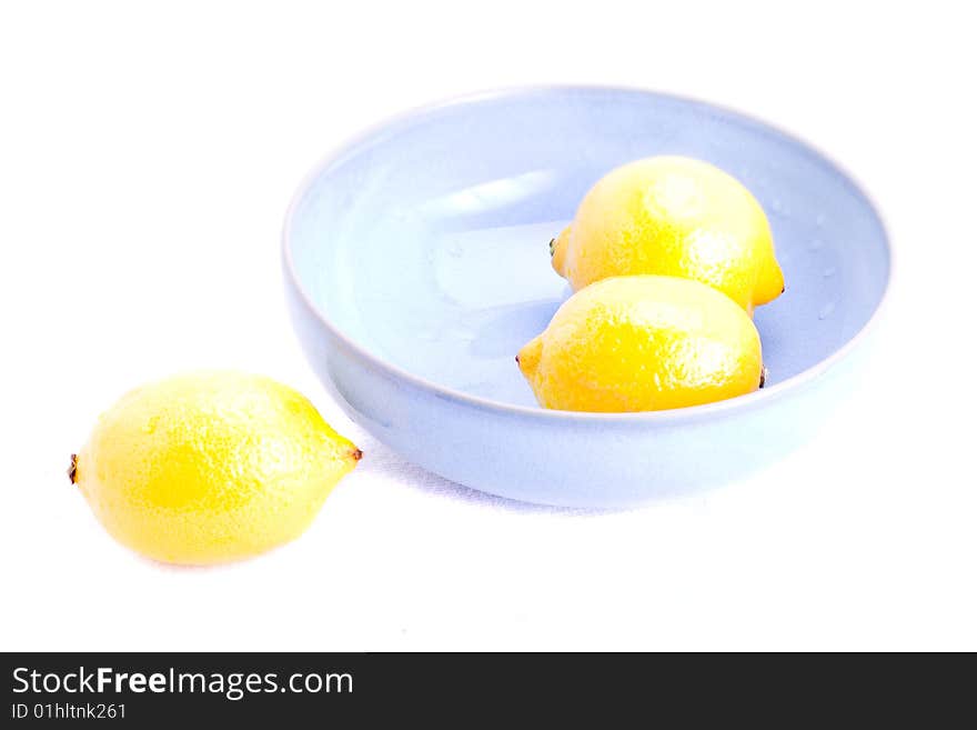 Fresh lemons in a blue bowl on white. Fresh lemons in a blue bowl on white