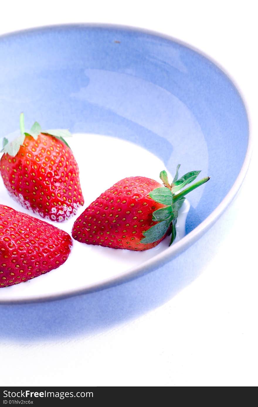 Three fresh leafed strawberries in a bowl of cream. Three fresh leafed strawberries in a bowl of cream