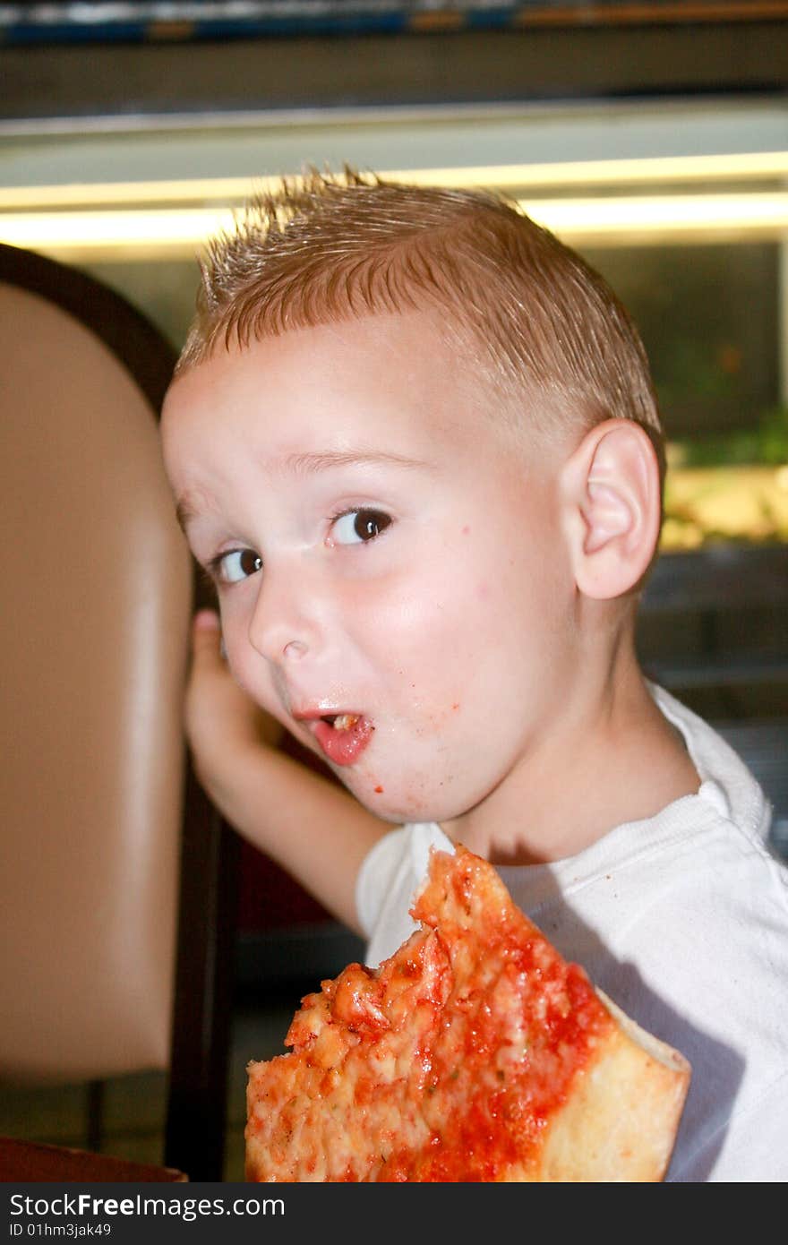 A young boy enjoying a slice of pizza. A young boy enjoying a slice of pizza.