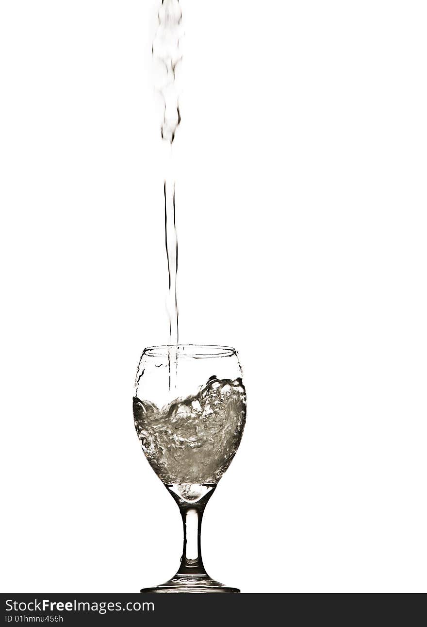 A stream of water splashing into and filling a wine glass. A stream of water splashing into and filling a wine glass.