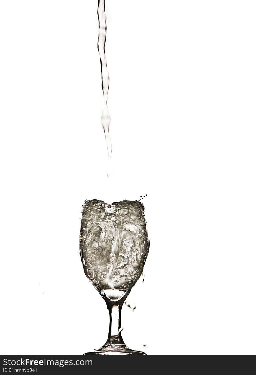 A stream of water splashing into and filling a wine glass. A stream of water splashing into and filling a wine glass.