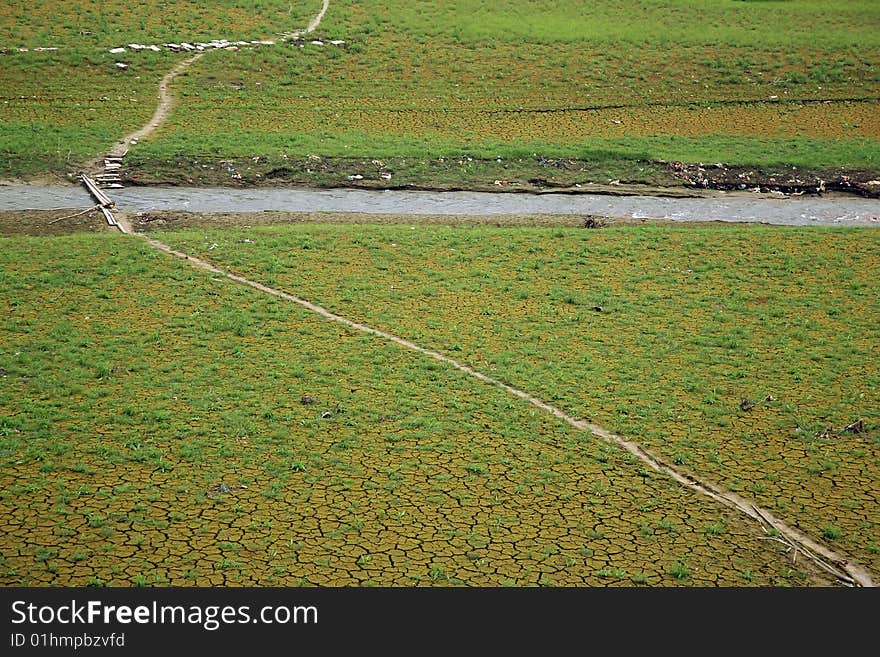 A narrow road going through a grass field and stream. A narrow road going through a grass field and stream.