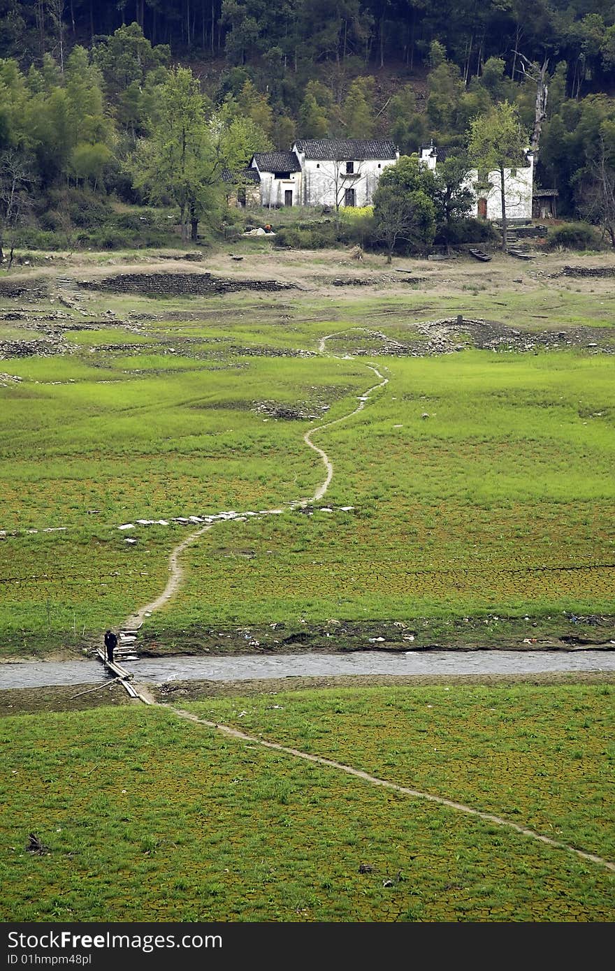 A narrow road going through a grass field and stream. A narrow road going through a grass field and stream.