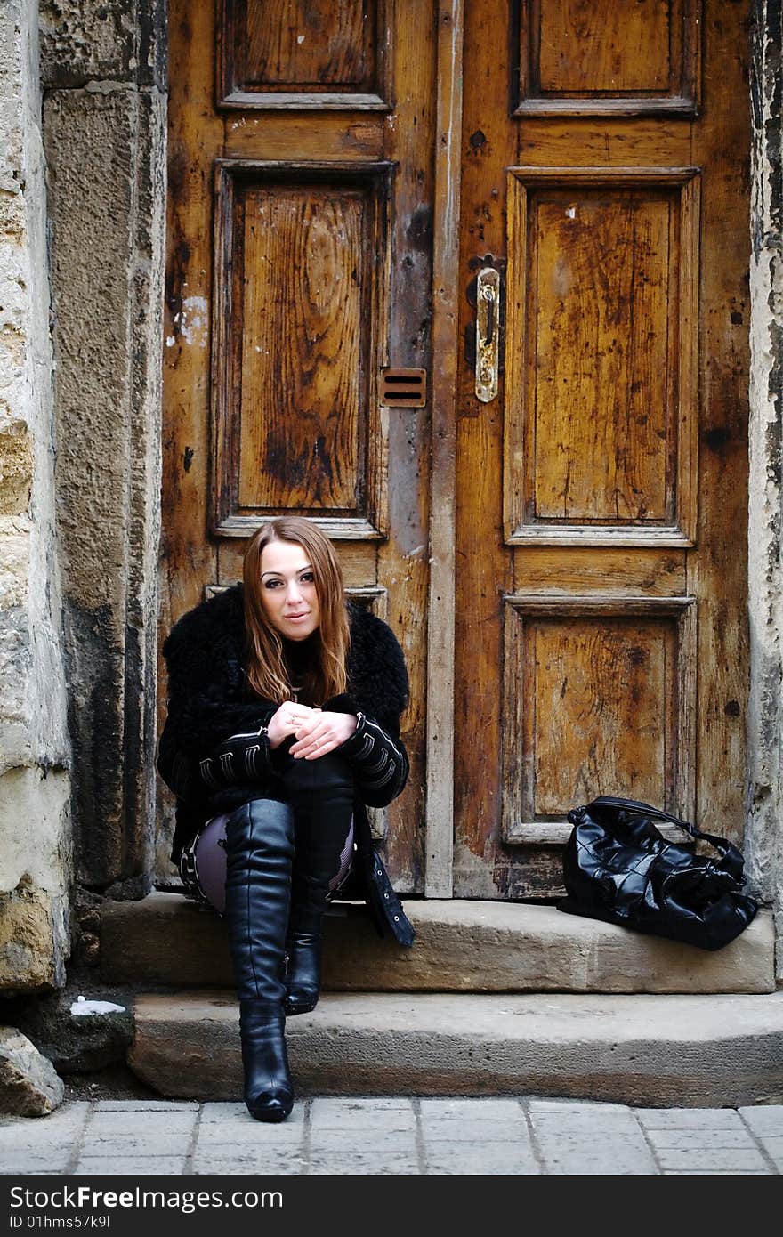 Stock photo: an image of a sad girl  sitting at the door