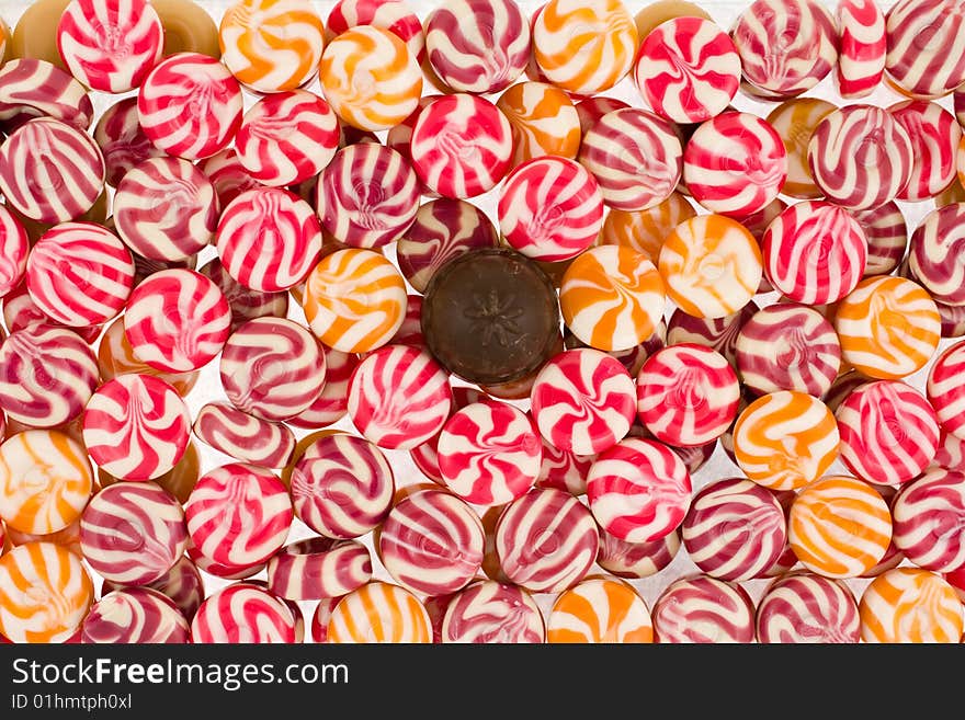 Background from round multi-coloured sweets with one chocolate sweet