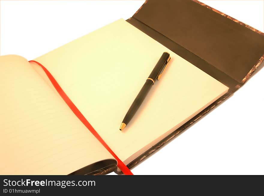 A pen lying on an open notebook, blank page showing. A pen lying on an open notebook, blank page showing