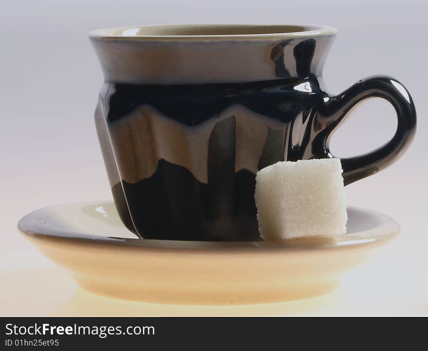 Black cup of tea and sugar isolated on a white background