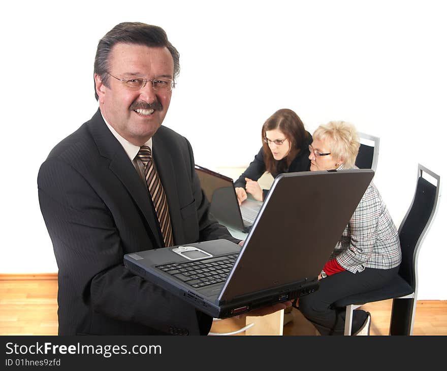 Businessman in office environment with laptop. Three people with focus on mature boss in front. Isolated over white. Businessman in office environment with laptop. Three people with focus on mature boss in front. Isolated over white.