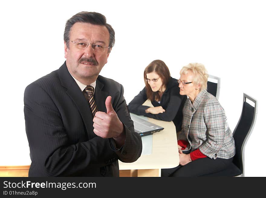 Businessman showing tumb up sign in office environment. Three people with focus on mature man in front. Isolated over white. Businessman showing tumb up sign in office environment. Three people with focus on mature man in front. Isolated over white.