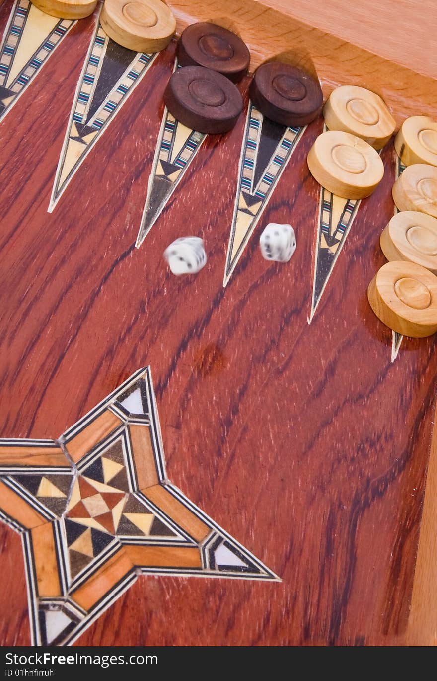 Two dices falling on wooden handmade backgammon board with chips and on white background. Two dices falling on wooden handmade backgammon board with chips and on white background