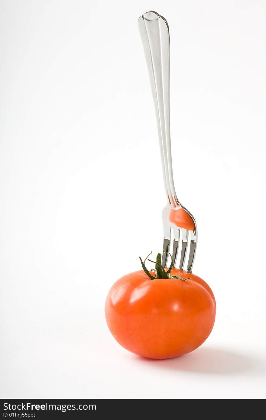 Tomato and fork on white background