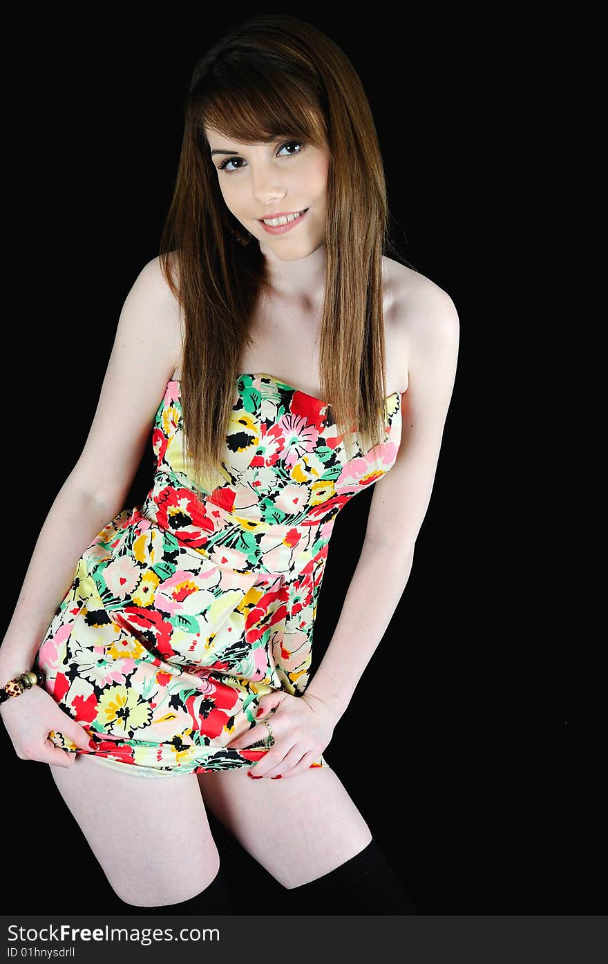 Female model standing against a black back drop smiling at the camera in a summery dress. Female model standing against a black back drop smiling at the camera in a summery dress