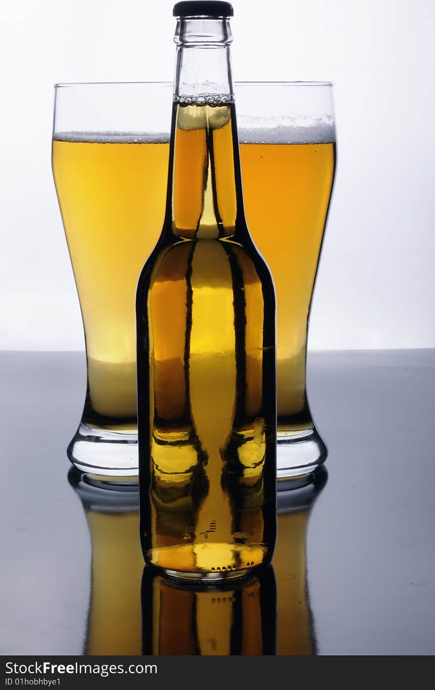 A bottle and two glasses of tasty gold beer. A bottle and two glasses of tasty gold beer