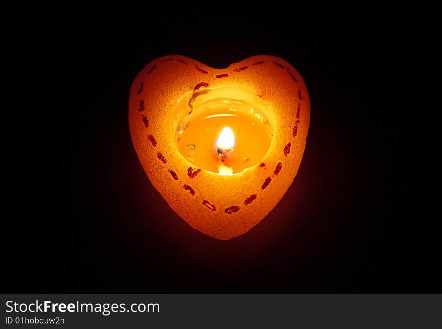 One flaring heart candle in dark