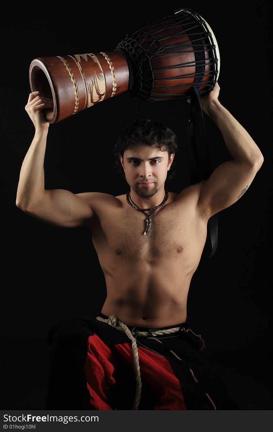 Handsome drummer playing the african drum. Shot in a studio. Handsome drummer playing the african drum. Shot in a studio.