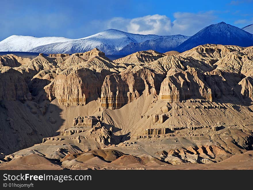 Clay mountains backgrounded with the snow-capped Himalayas