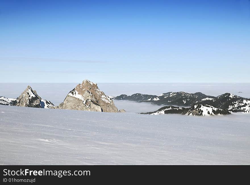 Flying above the alps where the mountain peaks are like islands in a sea of snow and clouds. Flying above the alps where the mountain peaks are like islands in a sea of snow and clouds