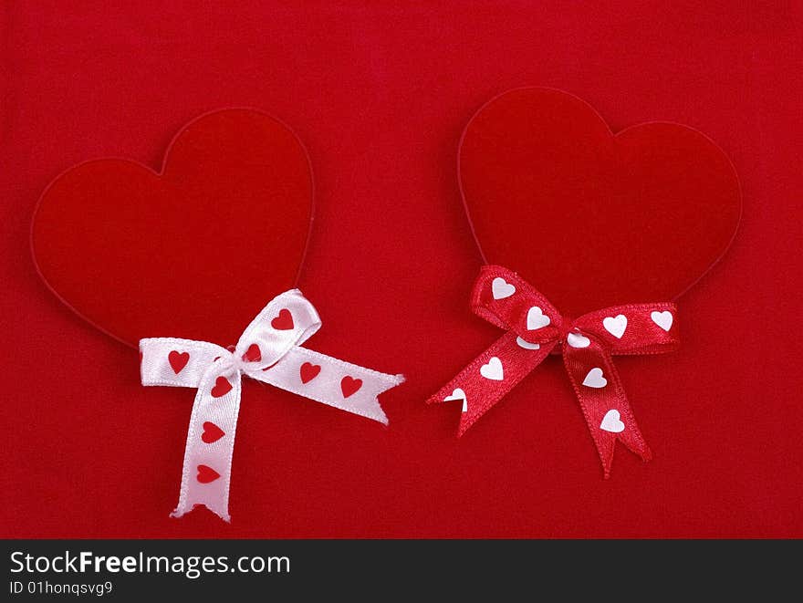 Two handmade hearts on red.