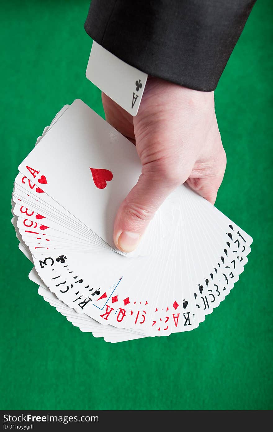 A fan of mixed playing cards on a green felt background with an ace up the sleeve. A fan of mixed playing cards on a green felt background with an ace up the sleeve