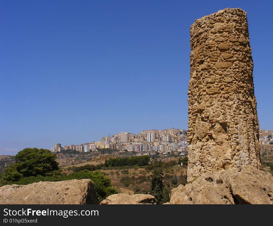 Column of an ancient greek temple and the city of Agrigento in the background. Column of an ancient greek temple and the city of Agrigento in the background