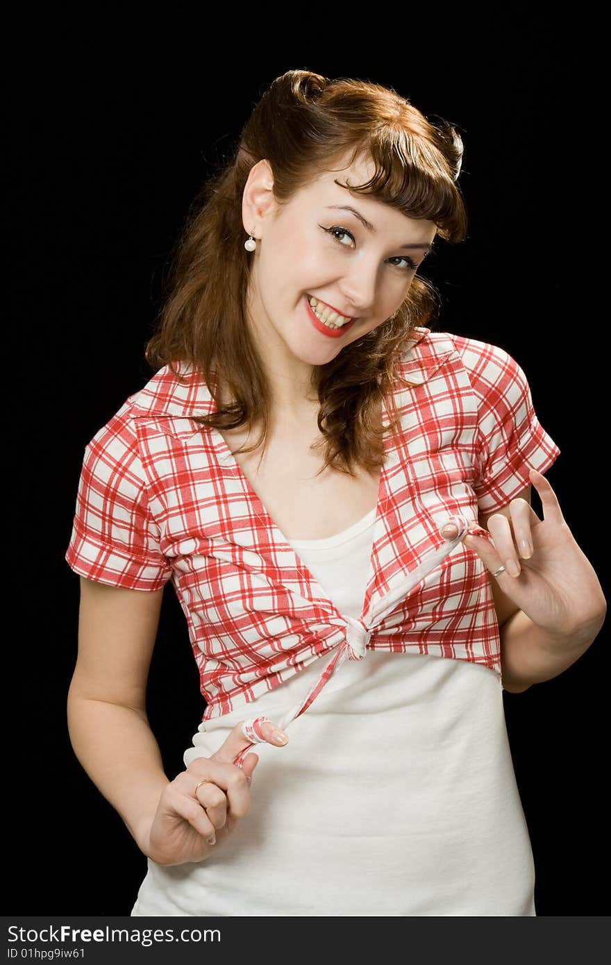 Pretty retro-style woman playing with her chequered blouse, smiling and looking at the camera over dark background. Pretty retro-style woman playing with her chequered blouse, smiling and looking at the camera over dark background