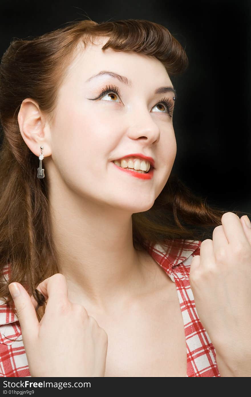 Pretty retro-style woman touching her hair, smiling and looking up over dark background. Pretty retro-style woman touching her hair, smiling and looking up over dark background