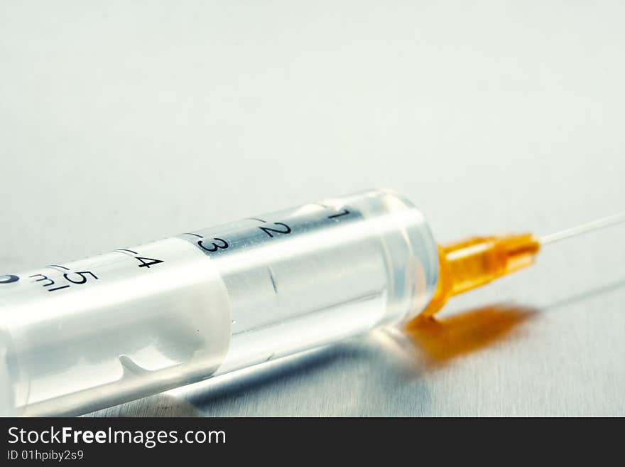 Syringe with hypodermic needle metal background. Syringe with hypodermic needle metal background