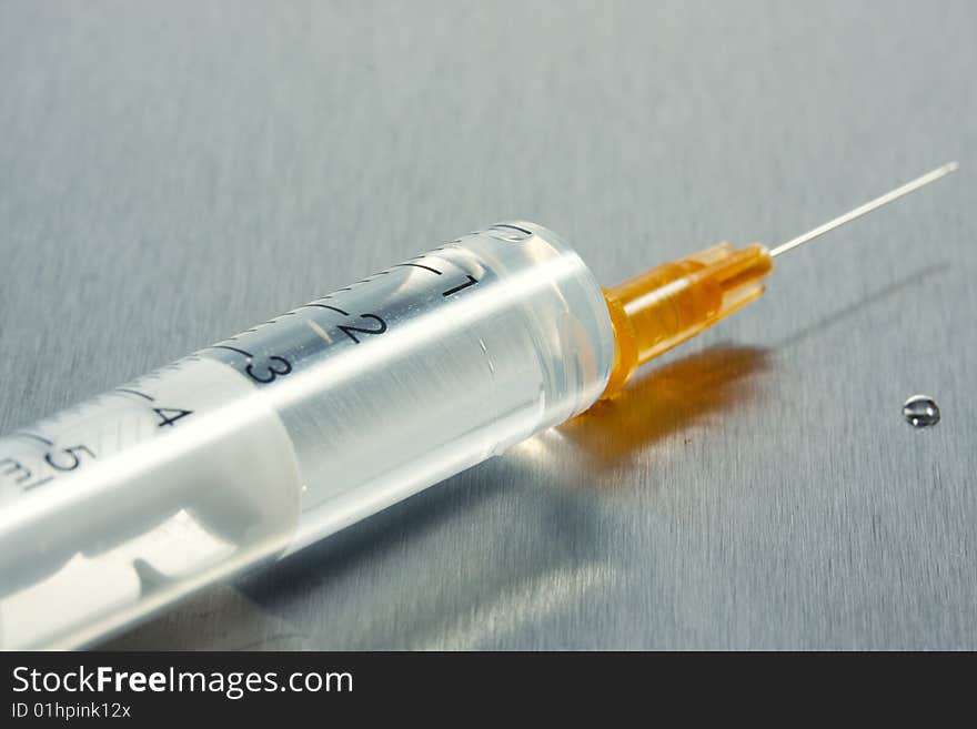 Syringe with hypodermic needle metal background. Syringe with hypodermic needle metal background