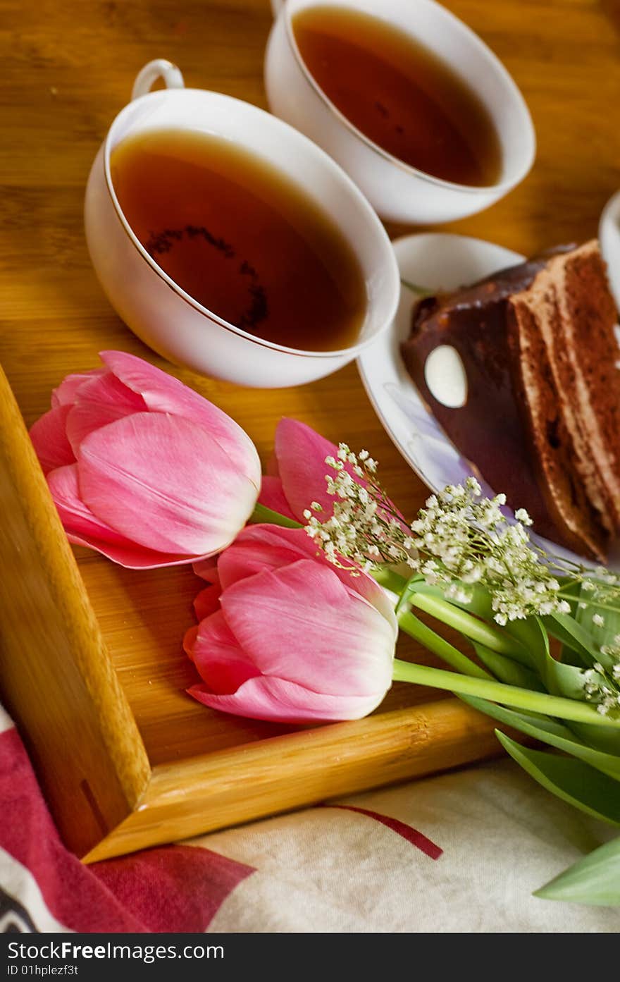 Breakfast tray on bed with tea, cakes and tulips. Breakfast tray on bed with tea, cakes and tulips