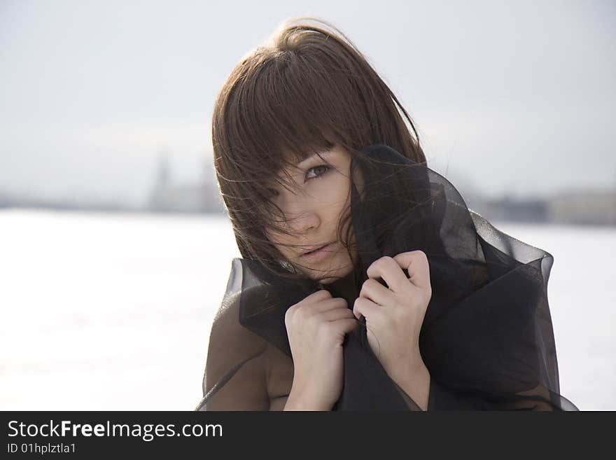 Picture of a girl in a black dress against a background of snow and the city. Picture of a girl in a black dress against a background of snow and the city