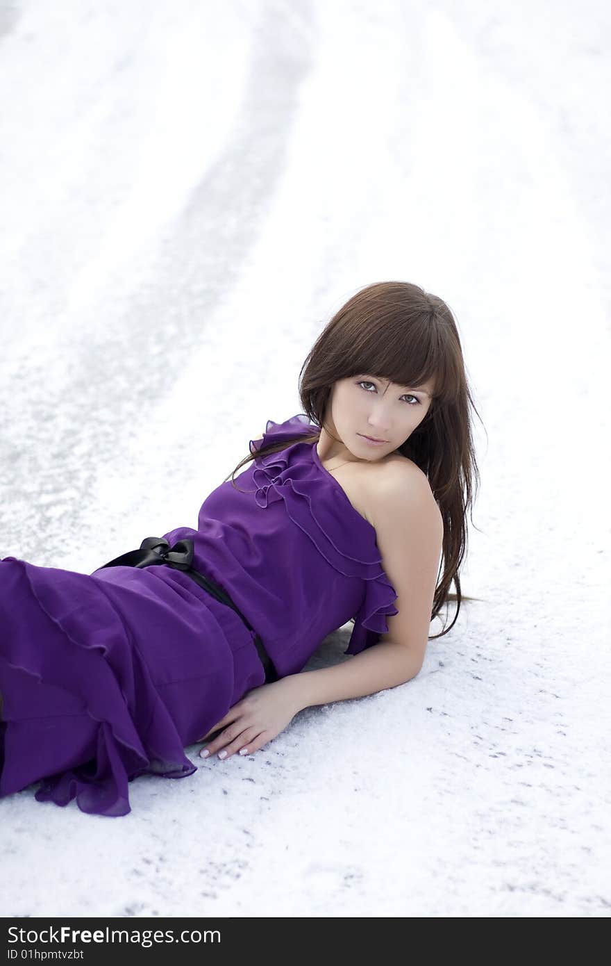 Picture of a girl who lies on the snow in the purple dress. Picture of a girl who lies on the snow in the purple dress
