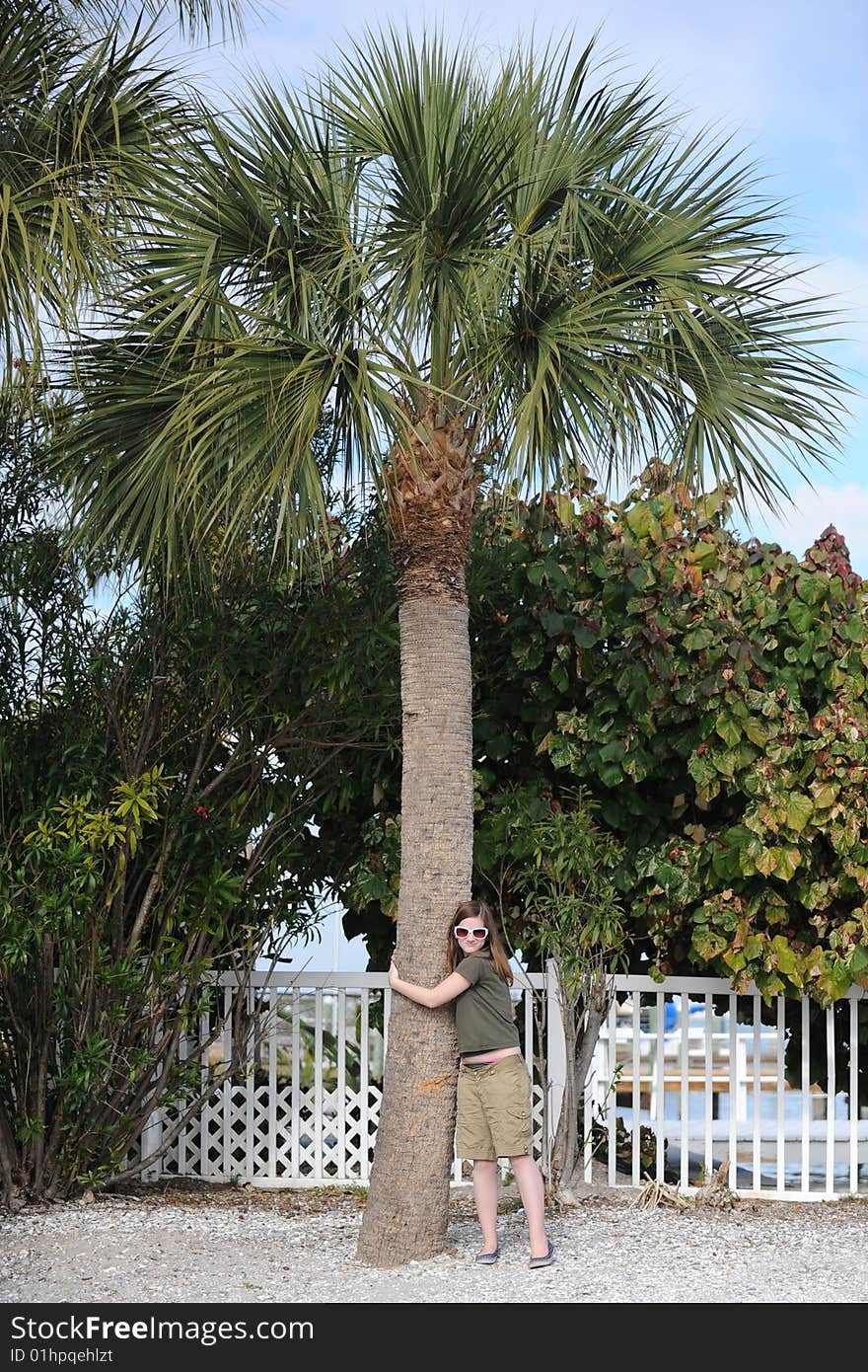 A northern preteen girl hugging a palm tree she's delighted to see for the first time. A northern preteen girl hugging a palm tree she's delighted to see for the first time.