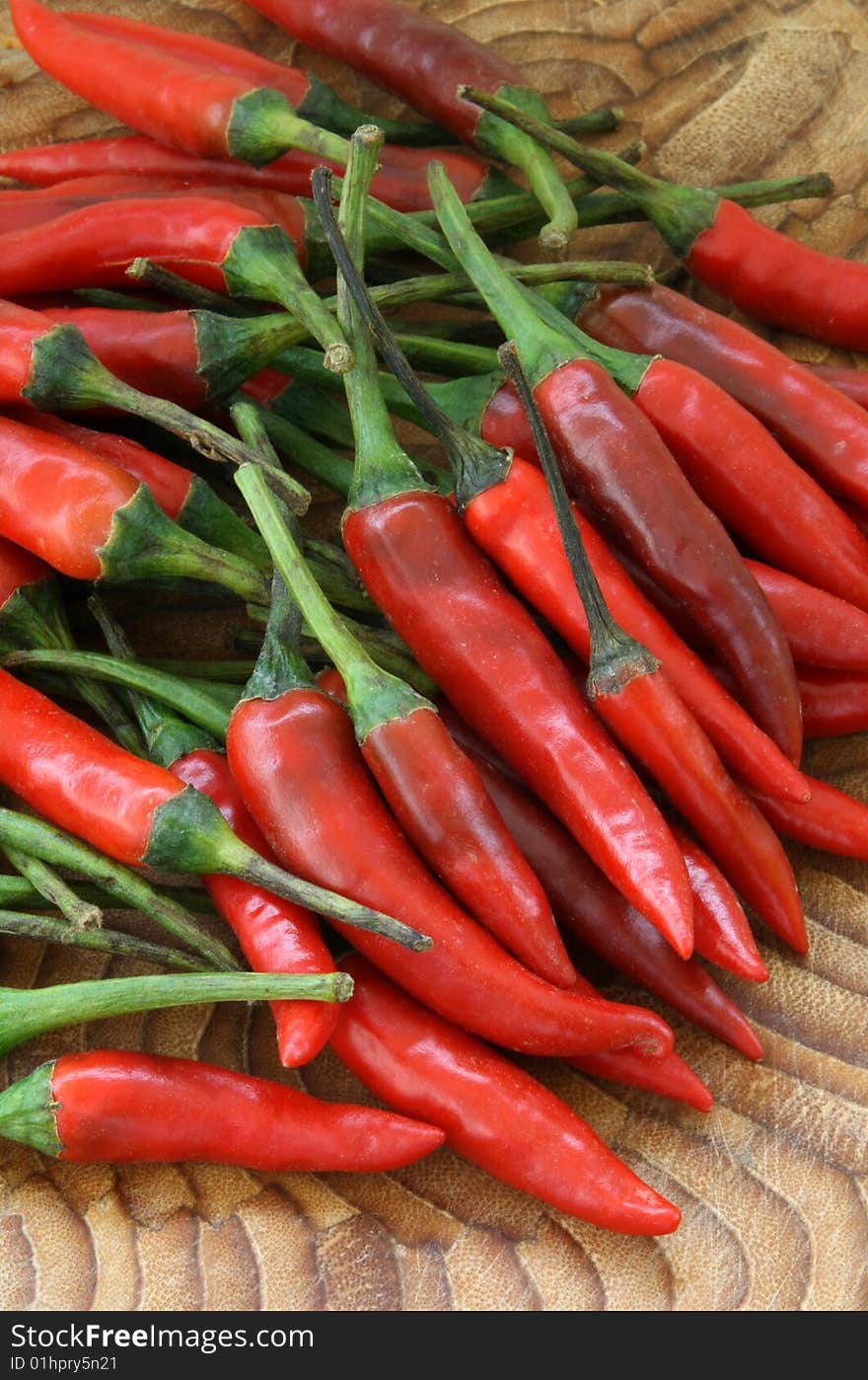 A pile of spcy red chilli peppers on a chopping board. A pile of spcy red chilli peppers on a chopping board