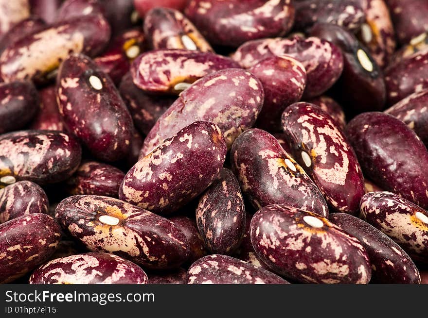 A couple of dark red and spotted kidney beans in wooden dish