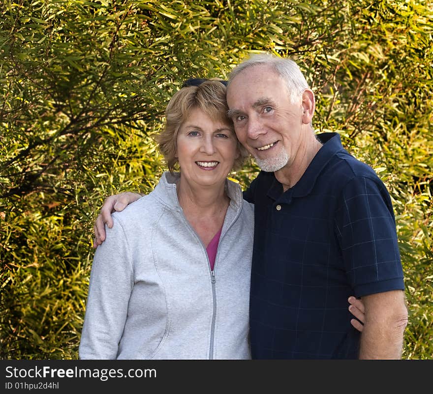 Happily married senior couple in front of lush foliage. Happily married senior couple in front of lush foliage