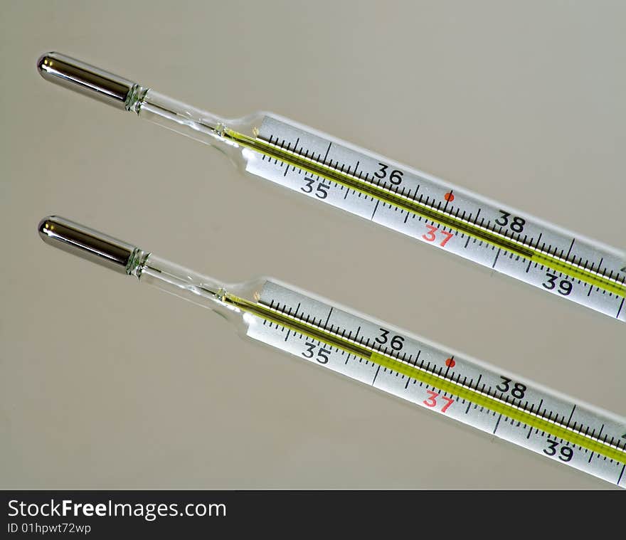 Two clinical thermometers marked in Celsius degrees, one shows body temperature lower than normal and another shows higher than normal.