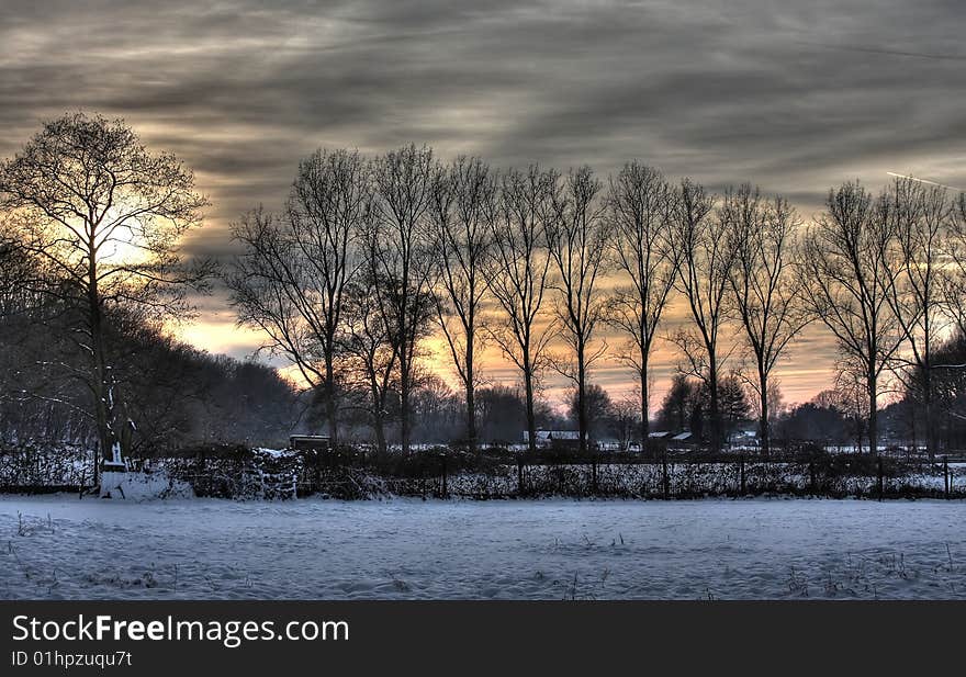 Sunset behind trees in winter scenery. Sunset behind trees in winter scenery