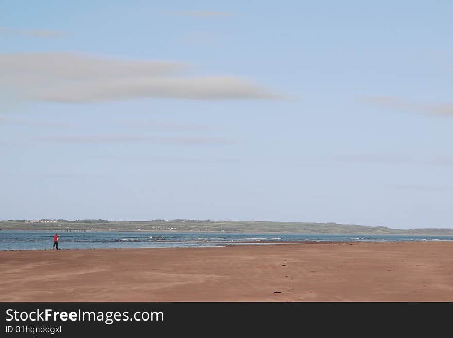 Man walking on beale beach co kerry ireland on a cold winters morning with turbines in the background. Man walking on beale beach co kerry ireland on a cold winters morning with turbines in the background