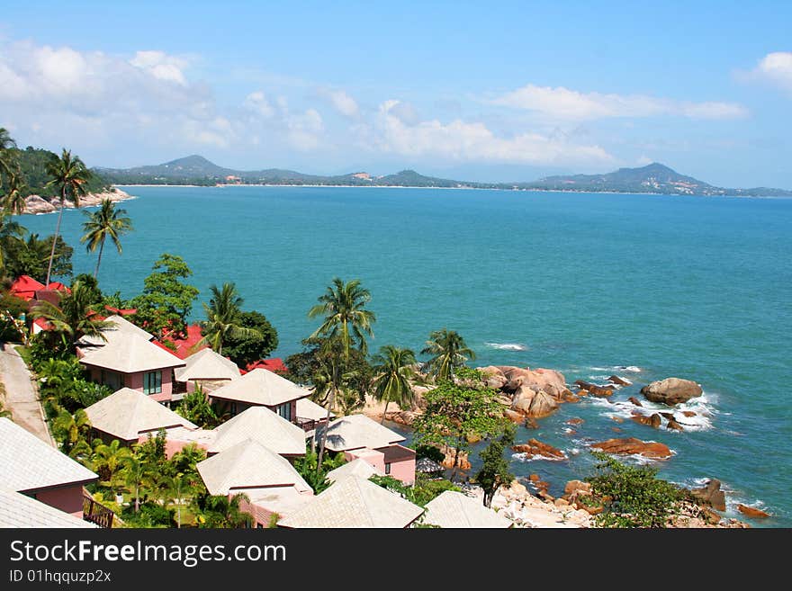 High view of tropical island coastline with homes and trees