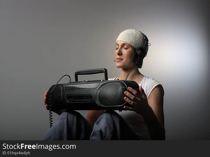 A cool looking girl listening music with stereo and headphones