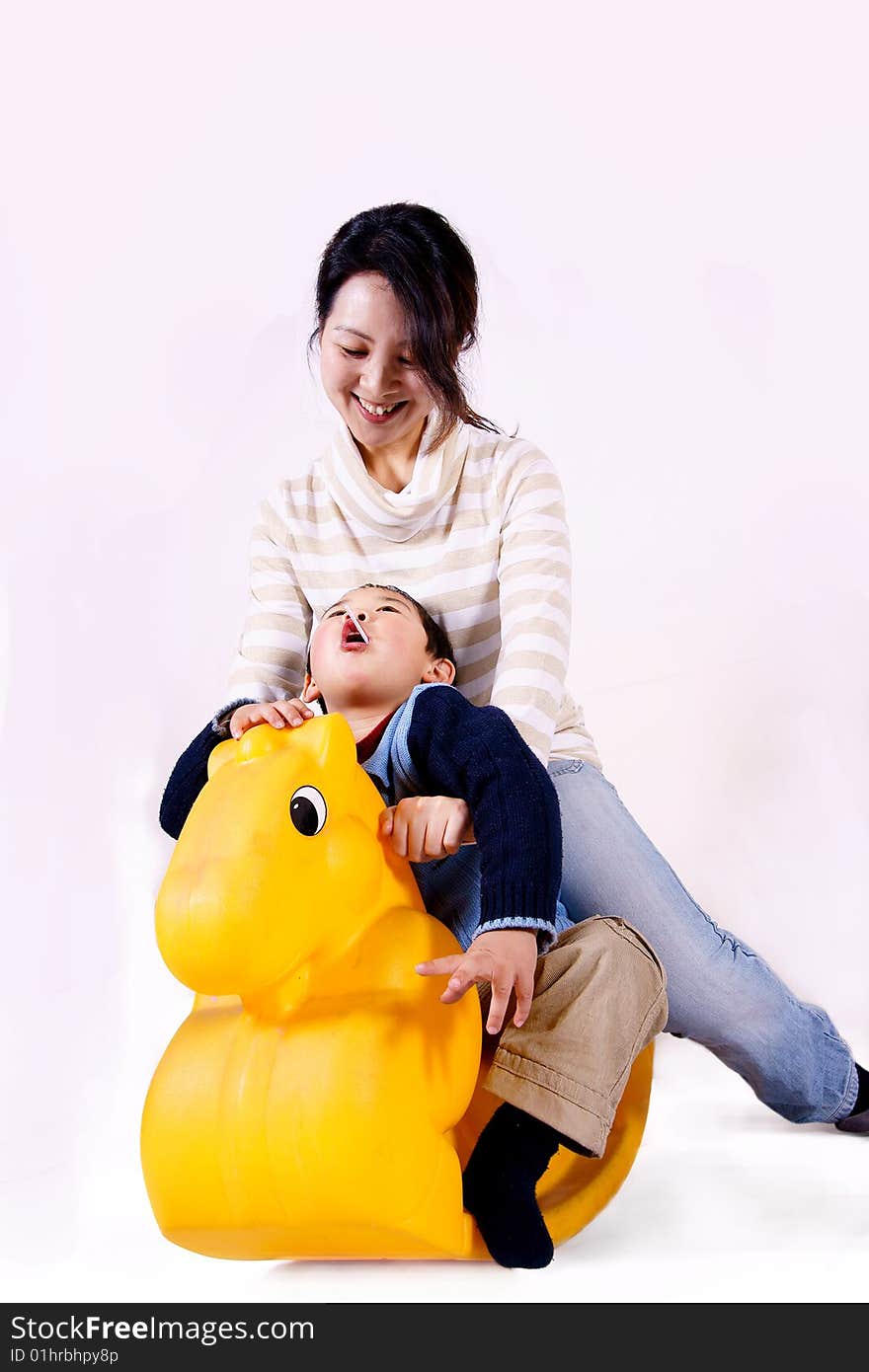 A picture of a chinese mother and child riding toy horse together and having great fun