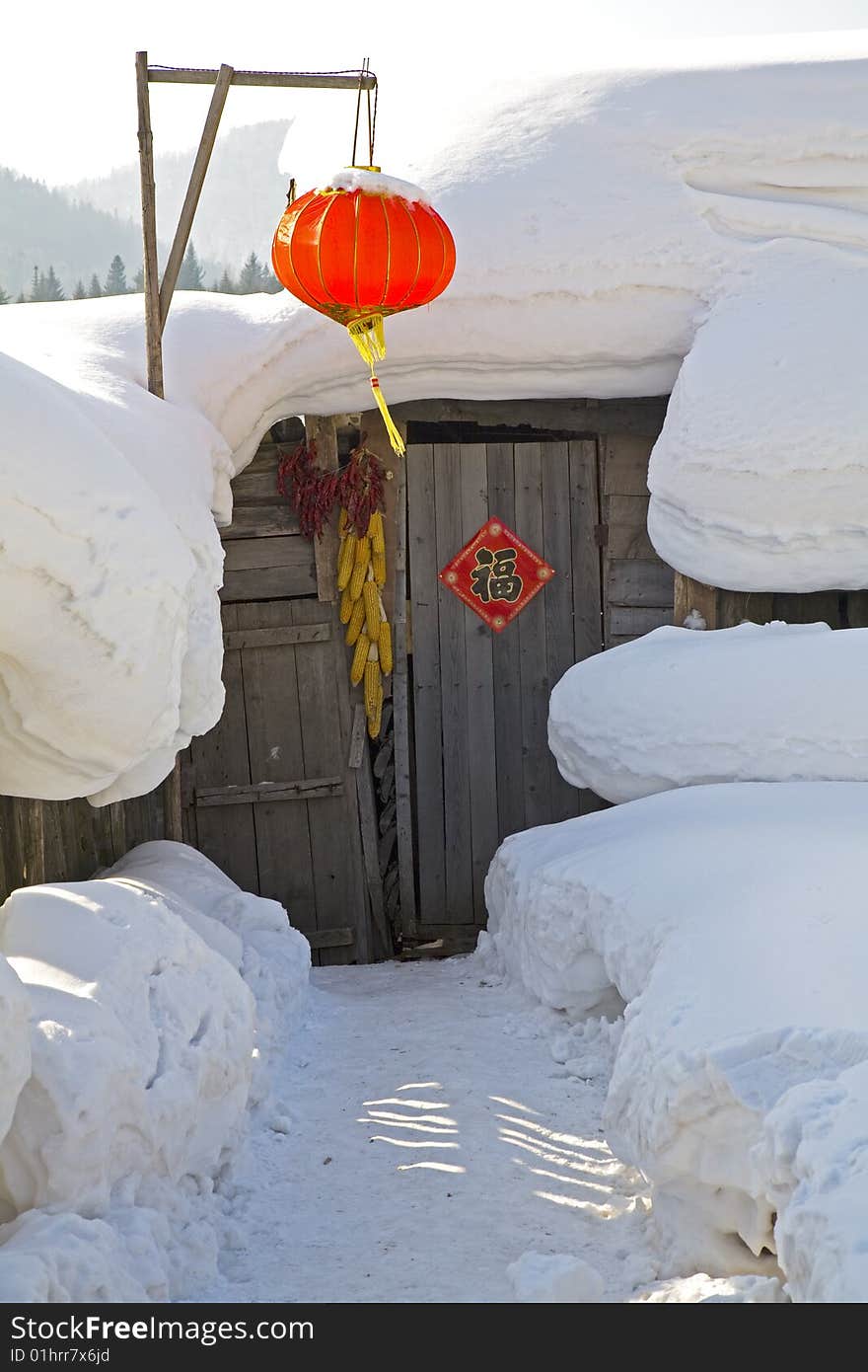 A red lantern  and a house covered in snow