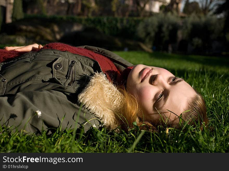 Girl in a red sweater, in a jacket on a green grass. Girl in a red sweater, in a jacket on a green grass