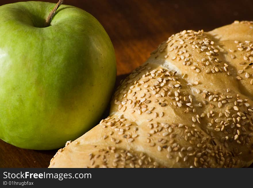 A bread loaf on a wooden table, with a green apple. A bread loaf on a wooden table, with a green apple