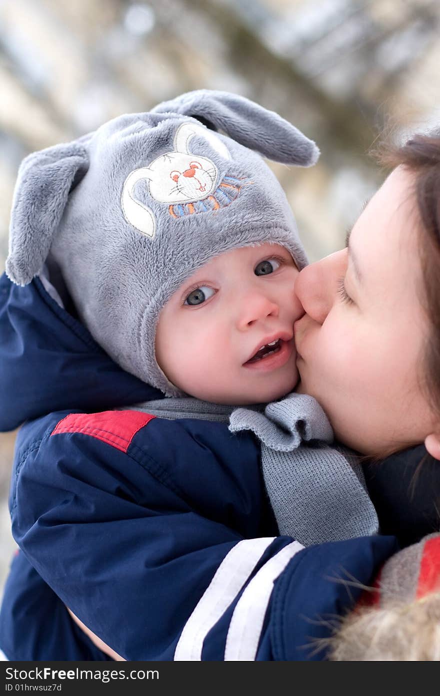 Portrait of young mother kissing small son outdoors. Portrait of young mother kissing small son outdoors