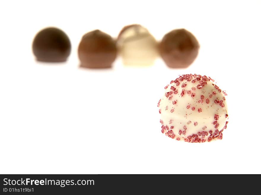 White chocolate praline with other pralines in the background. White chocolate praline with other pralines in the background.