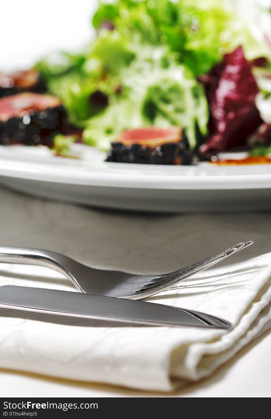 Fork and Knife with Salad on a Background. Selective Focus