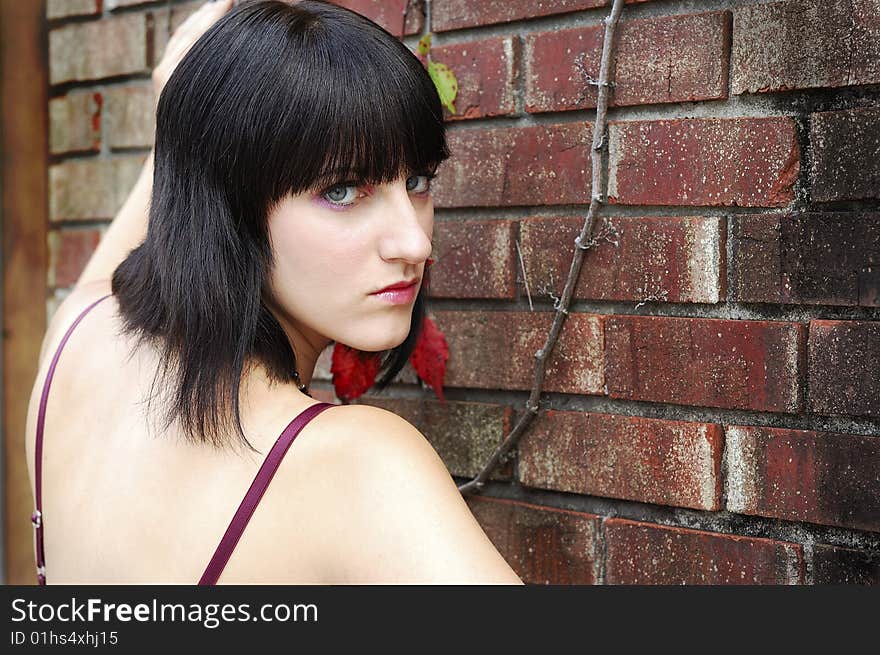 Young woman facing camera and standing in front of wall with upset look on her face. Young woman facing camera and standing in front of wall with upset look on her face