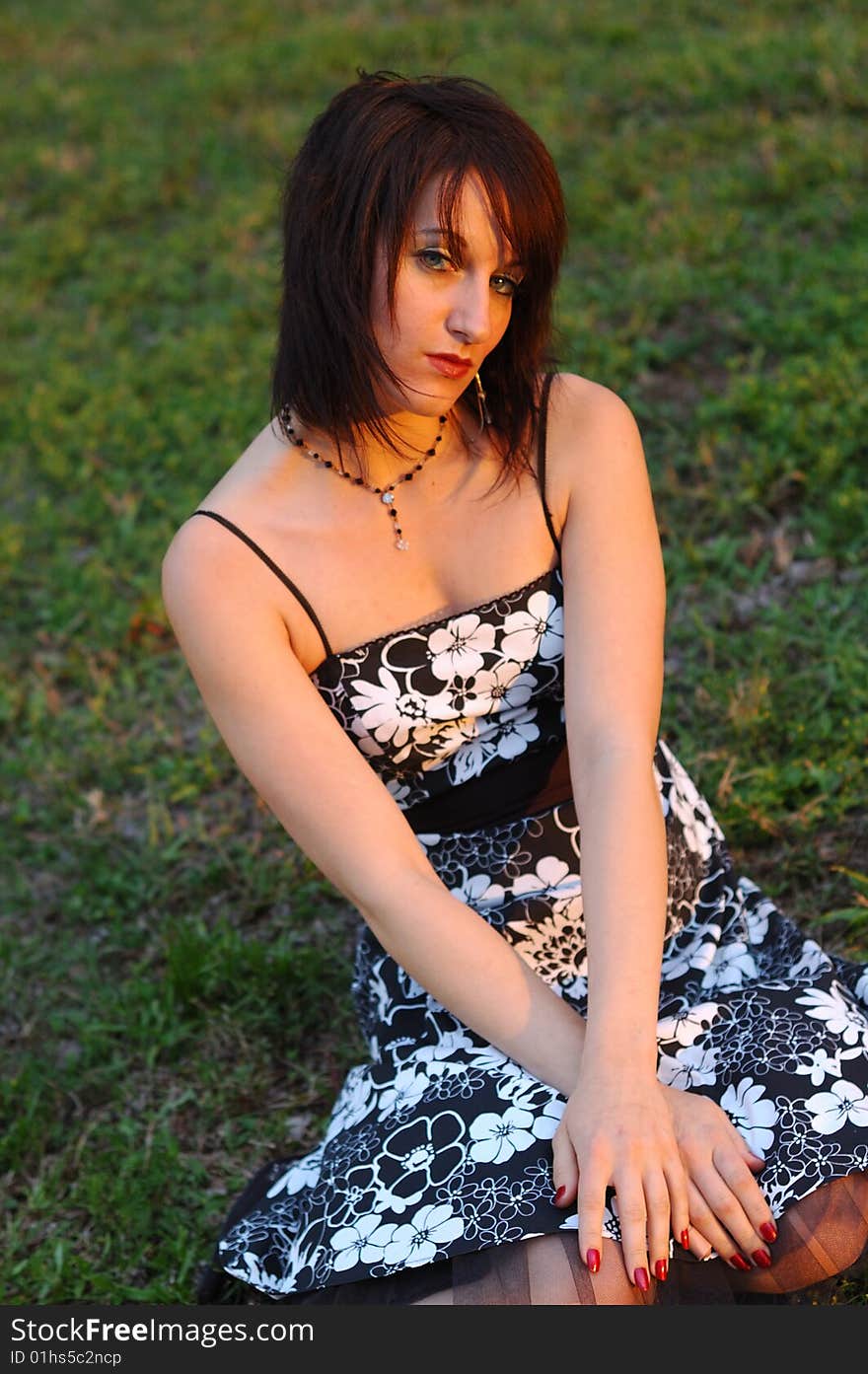 Young Woman kneeling in grass with warm sunset light cast upon her. Young Woman kneeling in grass with warm sunset light cast upon her