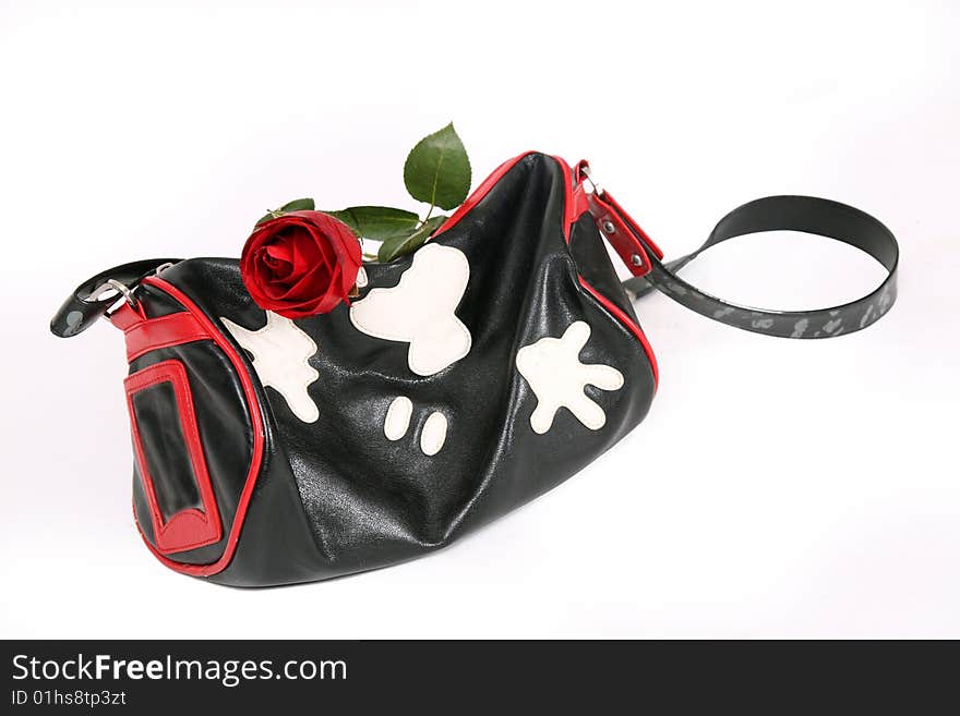 A fashionable handbag and a rose on white.